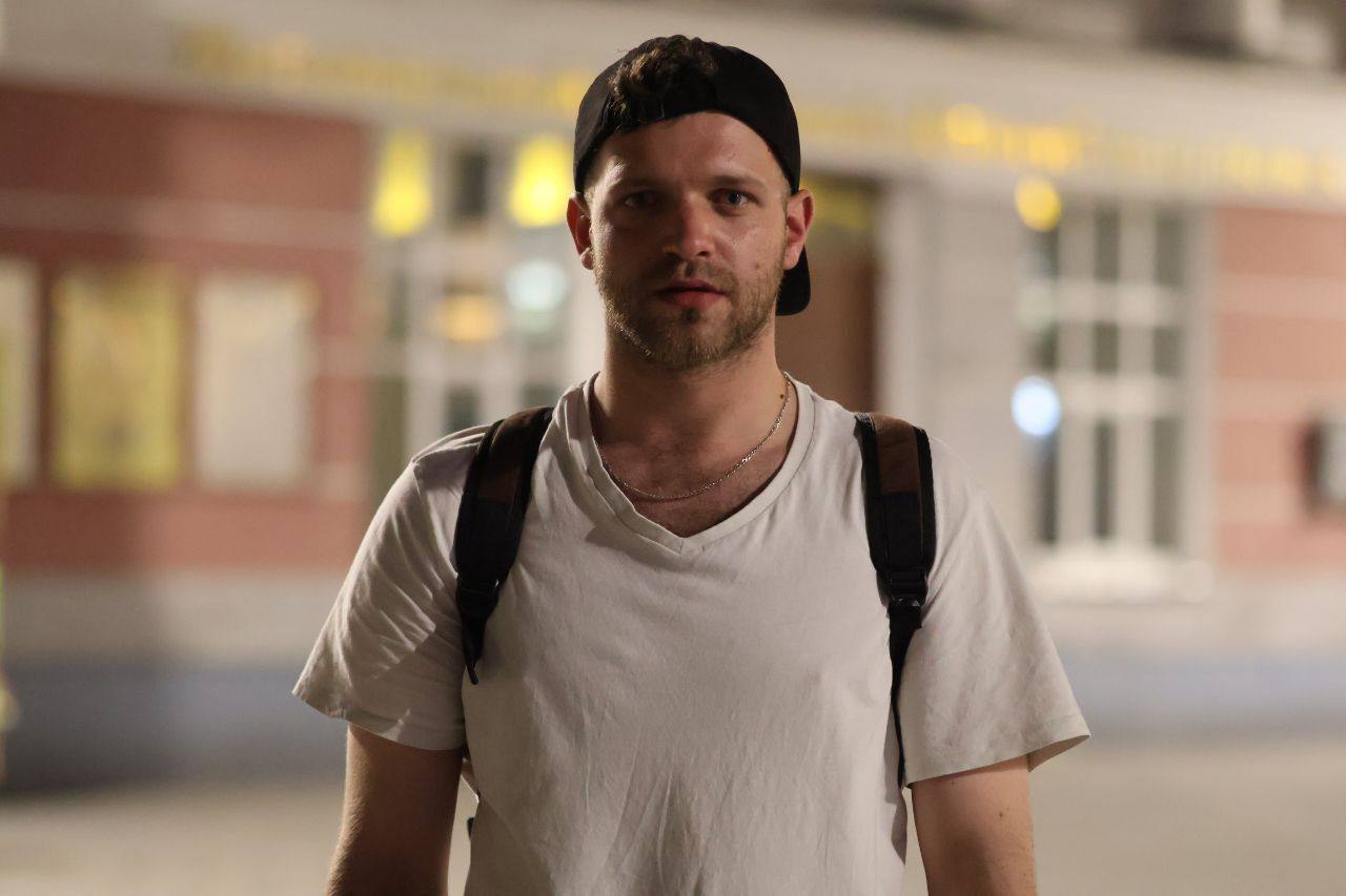 Man wearing a white t-shirt and black cap with a blurred background
