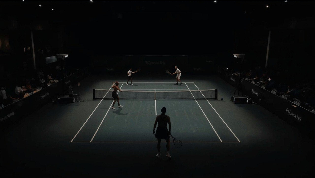Squash game in progress on a court with players and spectators in the dark.