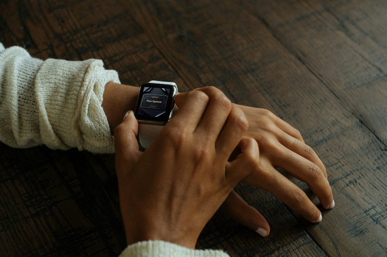 Person wearing a smartwatch on a wooden surface