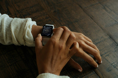 Person wearing a smartwatch on a wooden surface