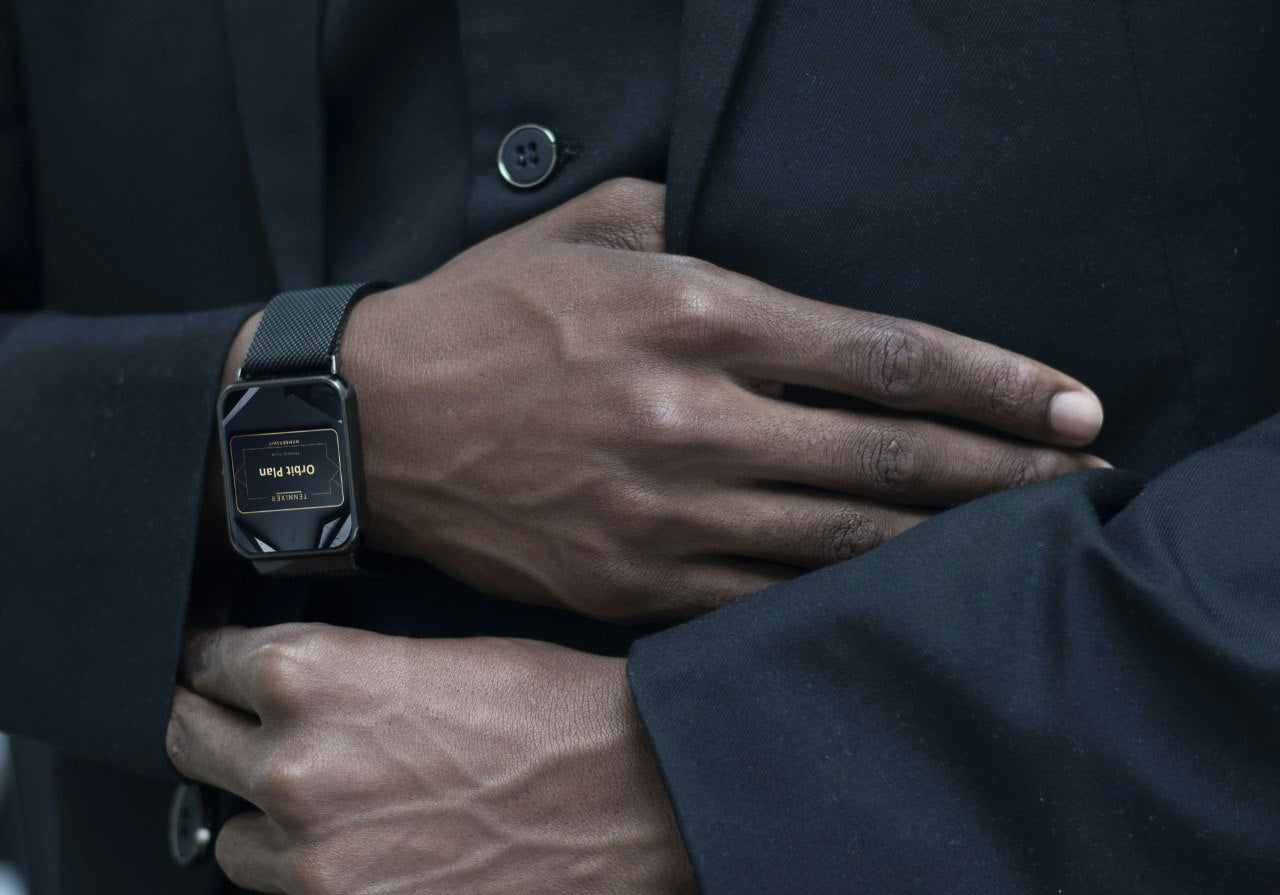 Person wearing a black suit with a watch on their wrist.